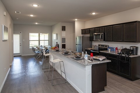 A kitchen with a white island and black cabinets.
