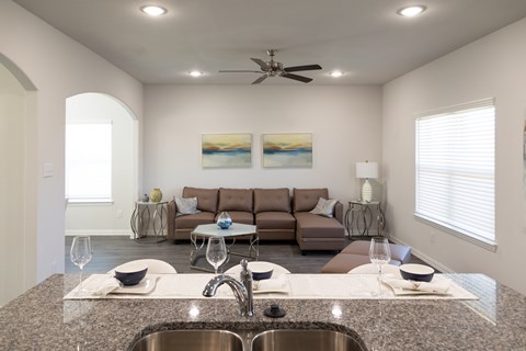 A modern kitchen with a large island and a brown sofa in the background.