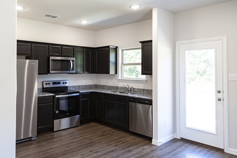 A kitchen with black cabinets and stainless steel appliances.