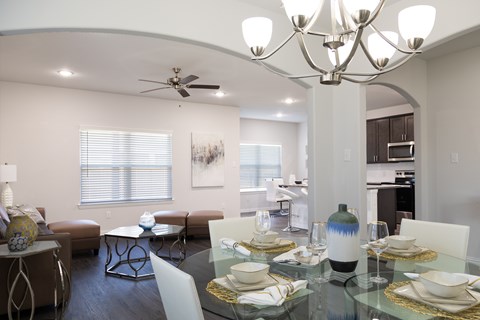 A modern dining room with a glass table set for two.