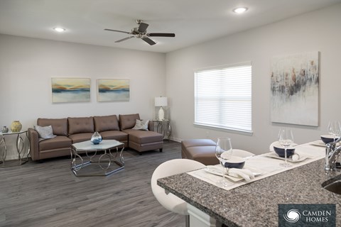 A living room with a brown couch, a coffee table, and a painting on the wall.