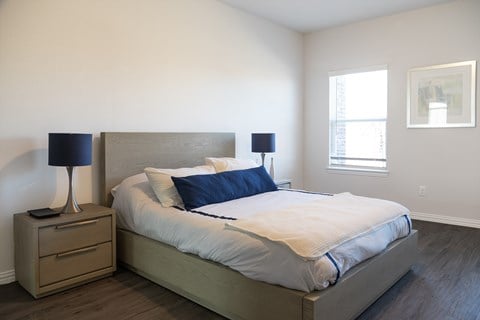 A bedroom with a bed, nightstand, and lamp.