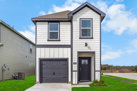 A two-story house with a garage door and a black door.