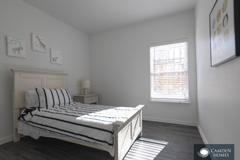 A bedroom with a bed, nightstand, and pictures on the wall.