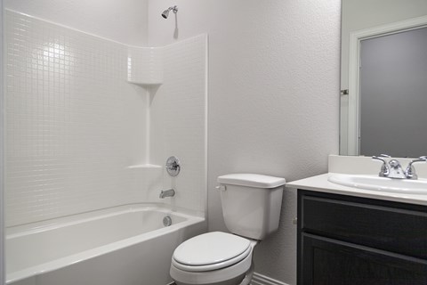 A white toilet sits next to a white bathtub in a bathroom.