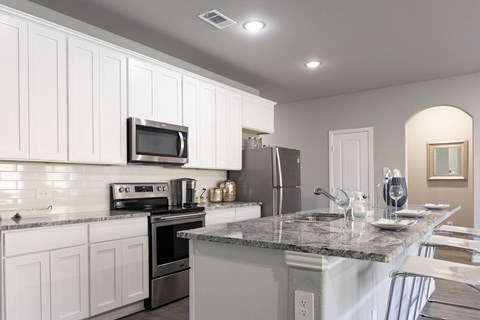 A modern kitchen with white cabinets and a granite countertop.