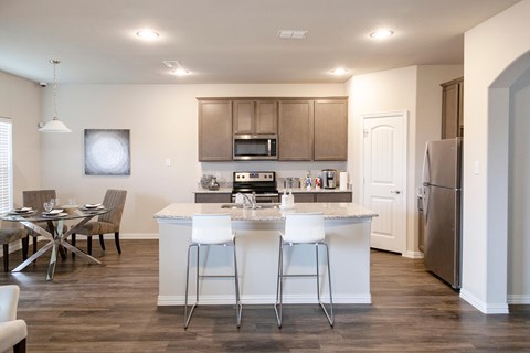 A kitchen with a white countertop and bar stools.