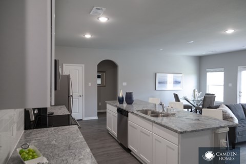 A modern kitchen with a marble countertop and a dining area with a table and chairs.