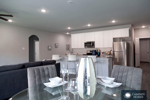 A modern dining room with a glass table and grey chairs.