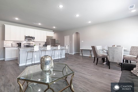 A modern kitchen with a glass table and a dining area with chairs.