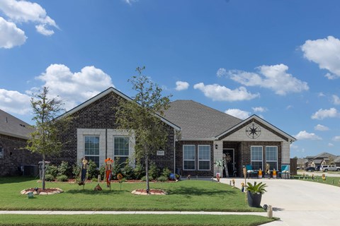 A house with a green lawn and a blue sky with clouds.