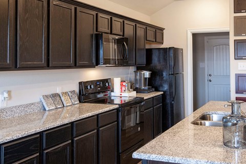 A kitchen with black cabinets and granite countertops.