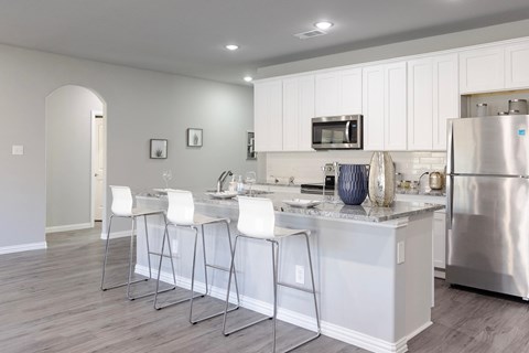 A kitchen with white cabinets and a stainless steel refrigerator.