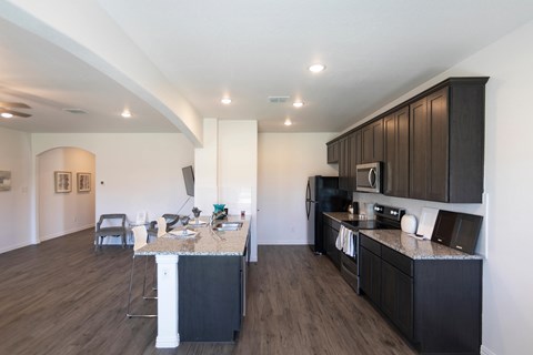 A kitchen with dark wood cabinets and a marble island.