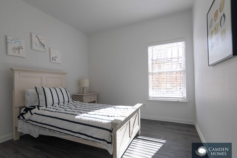 A bedroom with a bed, nightstand, and pictures on the wall.