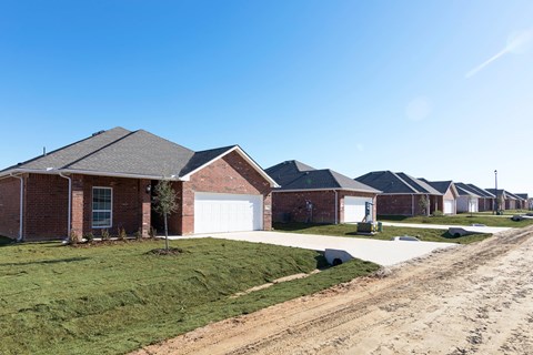 A row of houses with a dirt road in front.