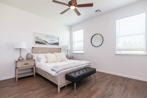 A bedroom with a bed, nightstand, and a ceiling fan.