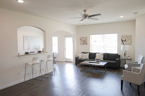 A living room with a black couch and a fan on the ceiling.