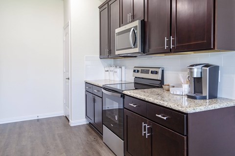 A kitchen with brown cabinets and a granite counter top.