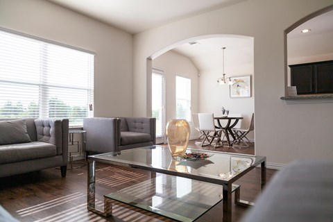 A modern living room with a glass coffee table and a grey sofa.