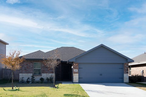 A house with a grey garage door and a brown brick exterior.