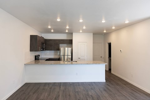 A kitchen with a white counter top and wooden floors.