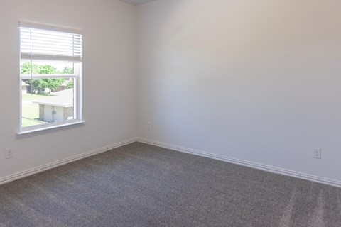 A room with a carpeted floor and a window.