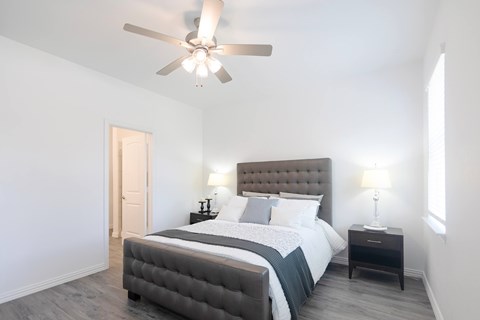 A bedroom with a large bed and a ceiling fan.