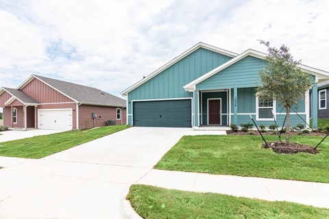 A blue house with a grey garage door is in the foreground.