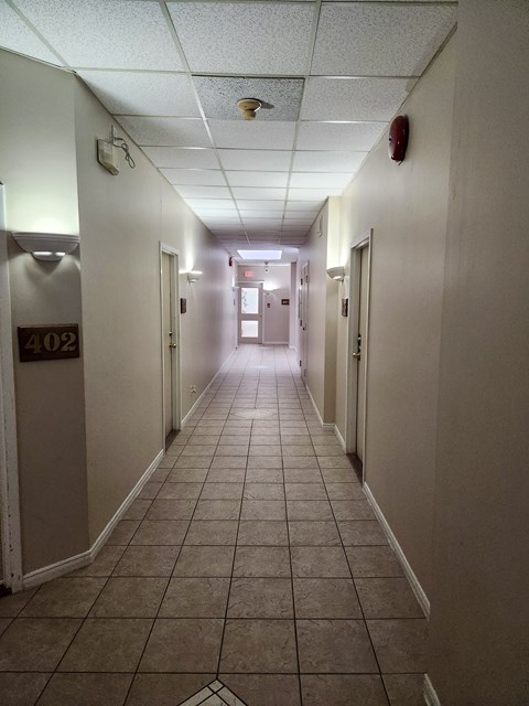 A long hallway with doors on both sides and a fire extinguisher on the wall.