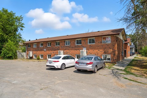 Two cars parked in front of a brick building.