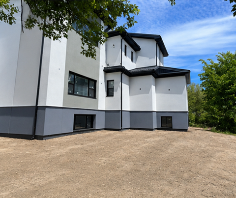 A modern building with a white and black exterior is surrounded by trees.