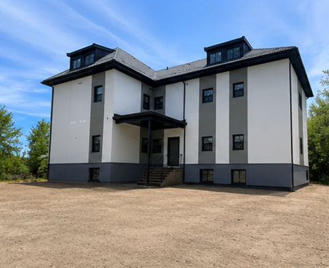 A large, two-story house with a black roof and white walls.