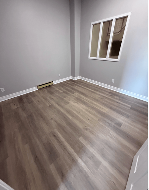 A room with wooden flooring and a window.