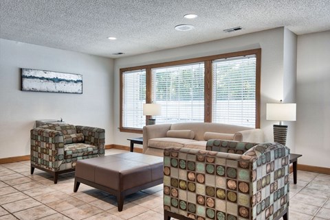 A living room with a couch, chair, ottoman, and lamp.