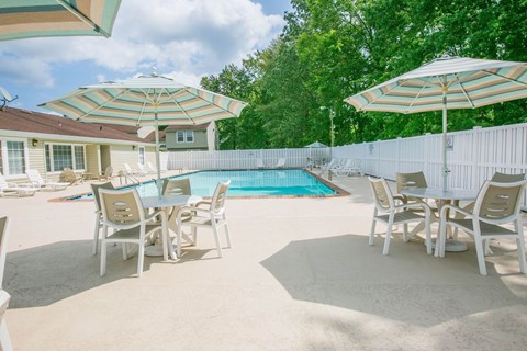 A poolside table set with chairs and umbrellas.