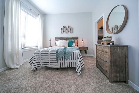 A bedroom with a bed, nightstand, and a dresser.