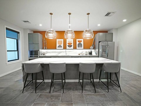 A modern kitchen with a long table and grey chairs.