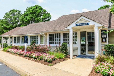 A leasing office building with a flower bed in front.