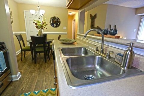 A kitchen with a large sink and a dining table with chairs.