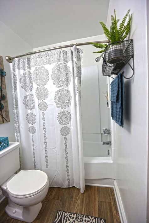 A white toilet in a bathroom with a shower curtain and a plant.