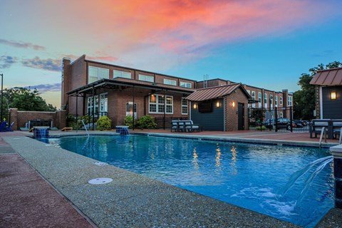 A swimming pool is surrounded by a brick building.