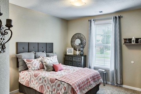 A bedroom with a large bed and a window with curtains.