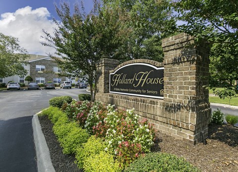 A brick sign that says Holland House in front of a building.