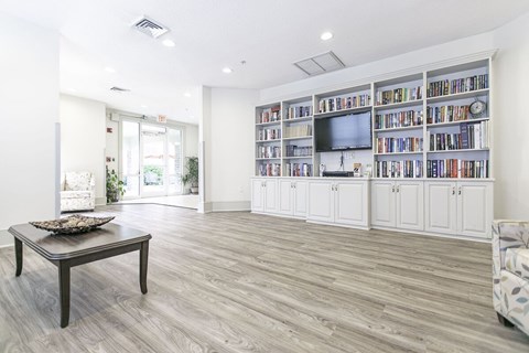 A living room with a wooden floor and a bookshelf filled with books.