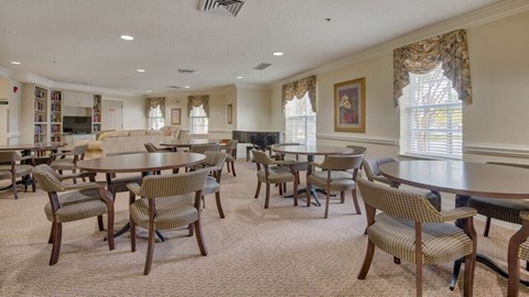 A dining room with a table surrounded by chairs.