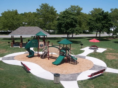 A playground with a green slide and a red slide.