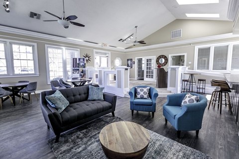 A living room with a black couch, blue chairs, and a wooden coffee table.
