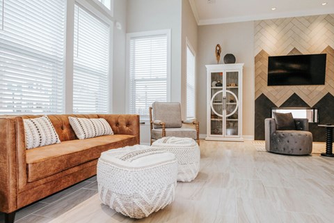 A living room with a brown couch and a white ottoman.