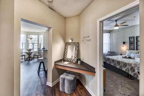 A bedroom with a bed, a desk with a chair, and a mirror on the wall.